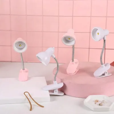 Multiple pink and white Mini Clip Study Lamp models displayed on a table against a pink tile background.
