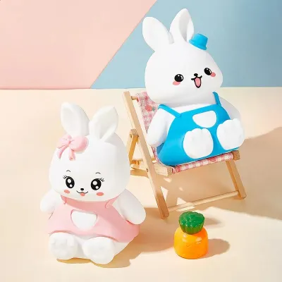 Blue Silicone Bunny Night Light resting on a mini wooden lounger chair beside pink bunny and carrot toy.